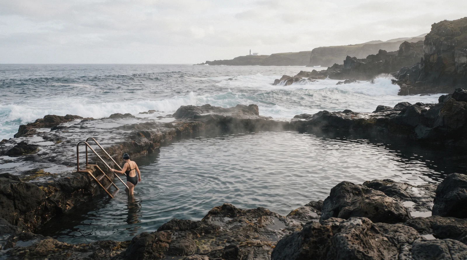 The natural thermal bathing pool at Ponta da Ferraria on the lava coast of São Miguel, with Atlantic swell breaking on the point