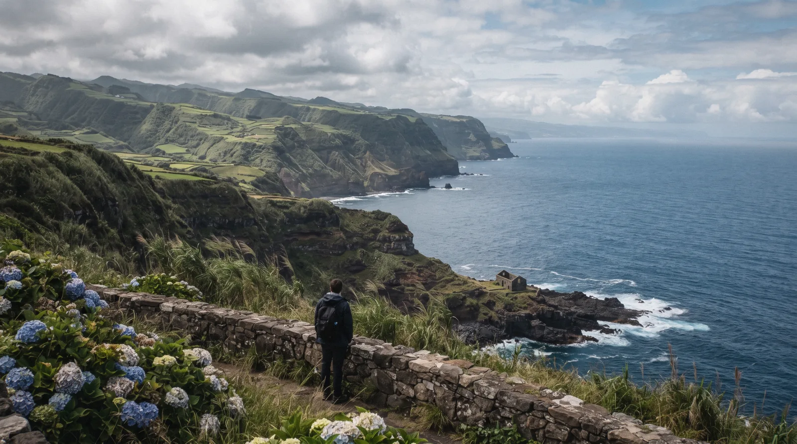 Green headlands and hydrangea-lined viewpoints on the northeast coast of São Miguel, with the ocean below and cloud moving over the ridges