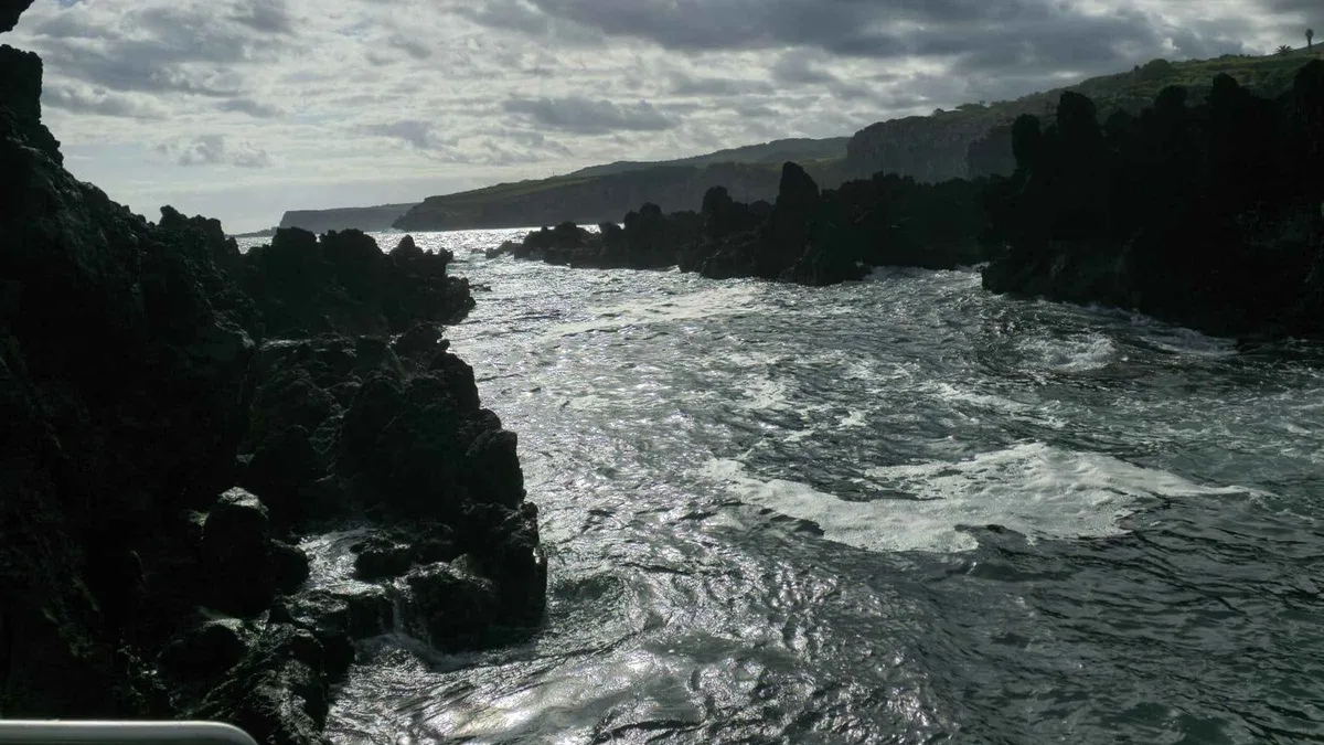 Waves breaking white over dark rocks at a bathing spot on the Terceira island coast