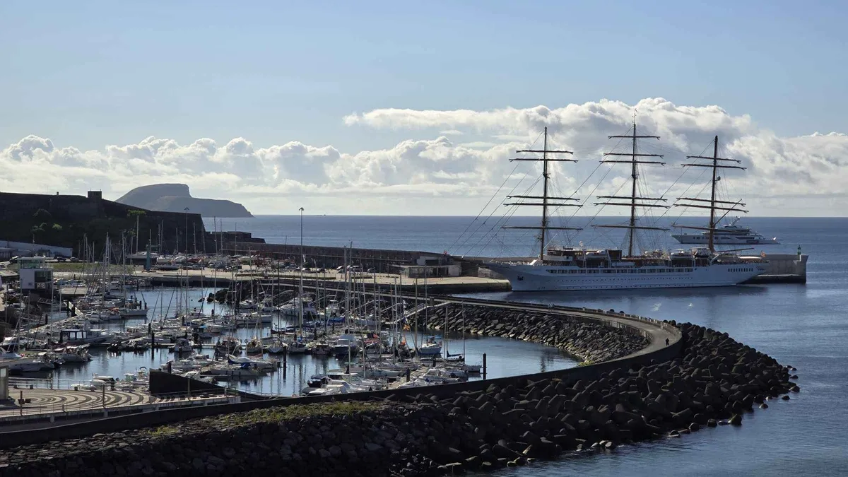 A tall ship moored in the marina of Angra do Heroismo with Monte Brasil rising behind