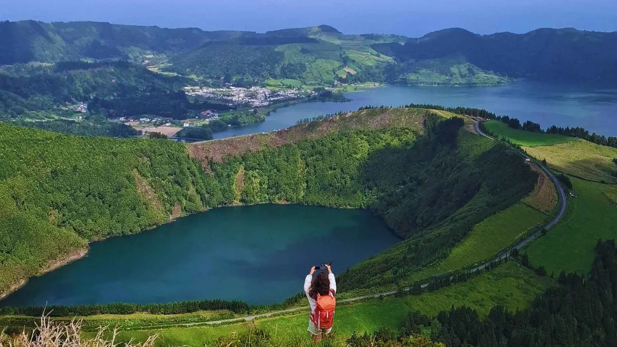 A traveler in red looking out over a crater lake at Sete Cidades on a private west island tour