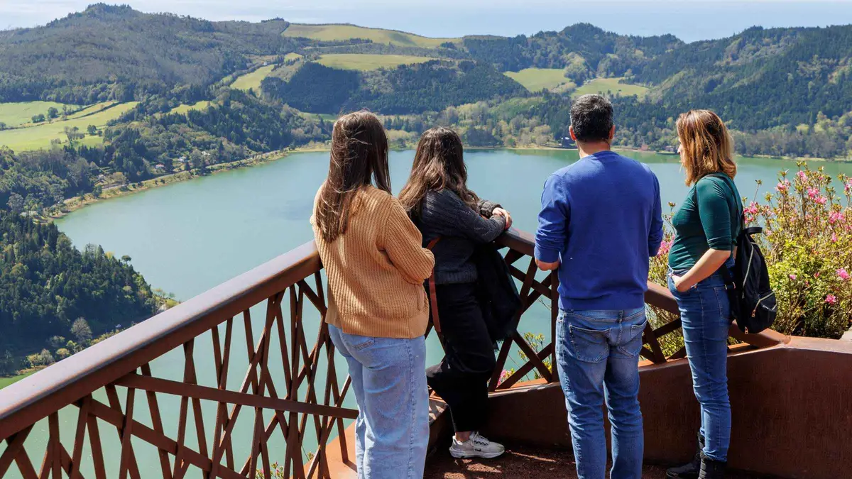 Four travelers at a railing viewpoint over the Furnas lake on an east island van tour