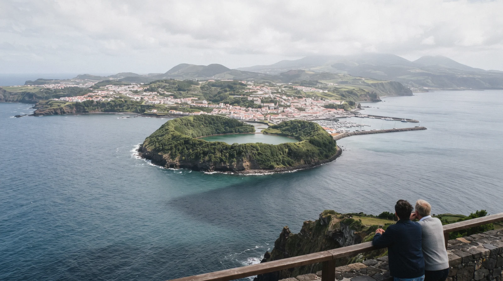 The circular crater islet of Vila Franca do Campo seen from above, its inner lagoon ringed by green walls, with the town and its marina on the coast behind