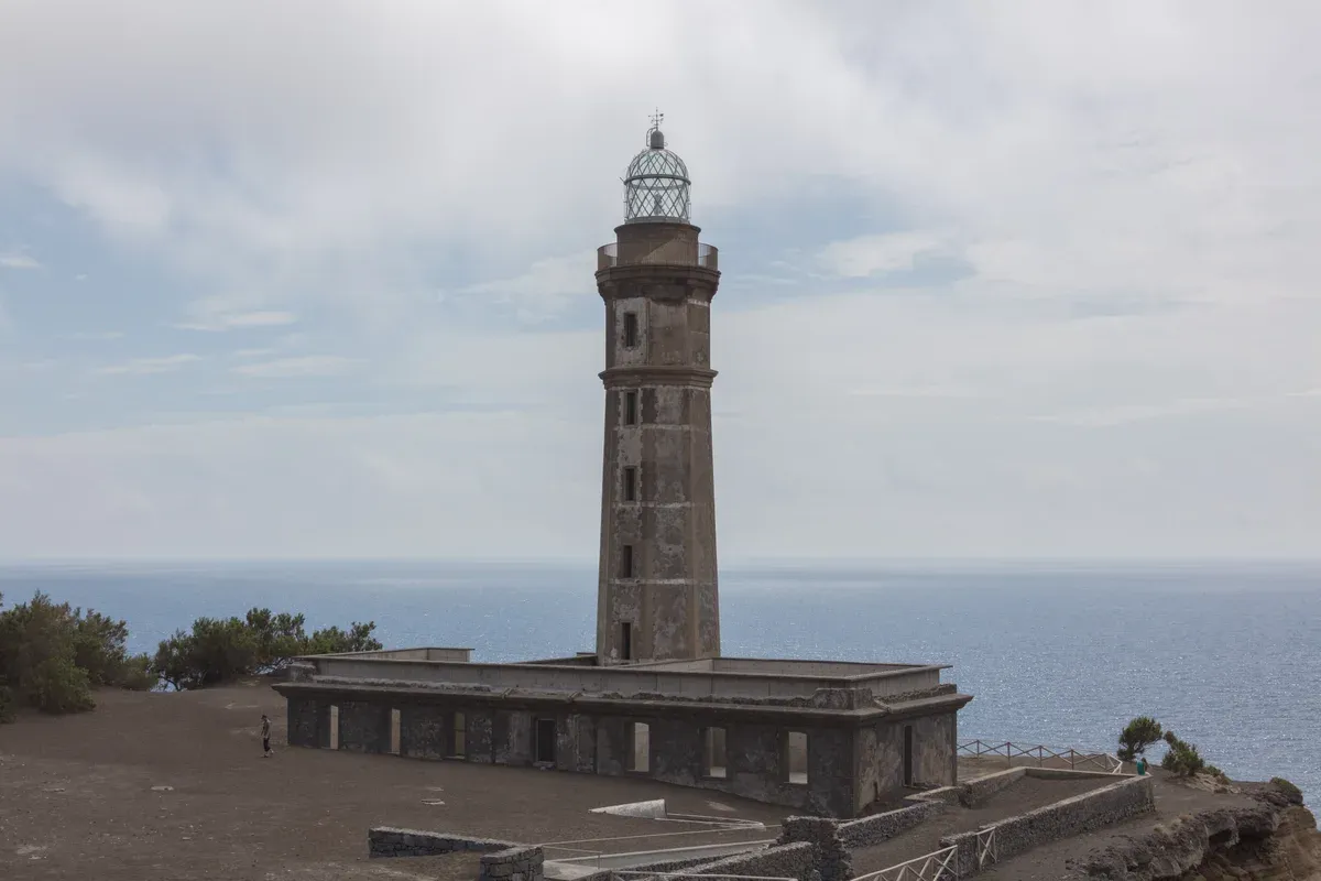 The old lighthouse tower of Capelinhos standing above the grey ash terrain on Faial island in the Azores