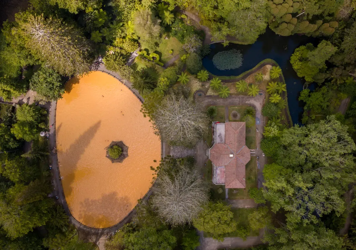 Aerial view of the orange iron thermal pool inside a botanical garden