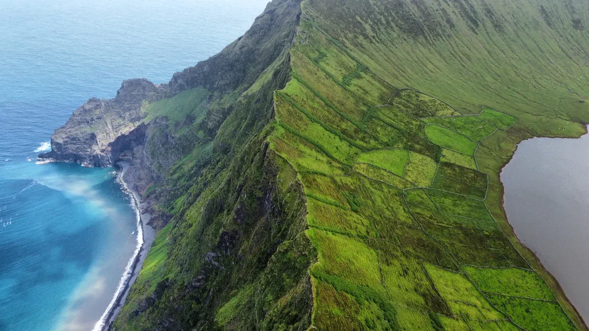 Green ridge of the Caldeirão crater on Corvo island with the crater lake and the ocean beyond