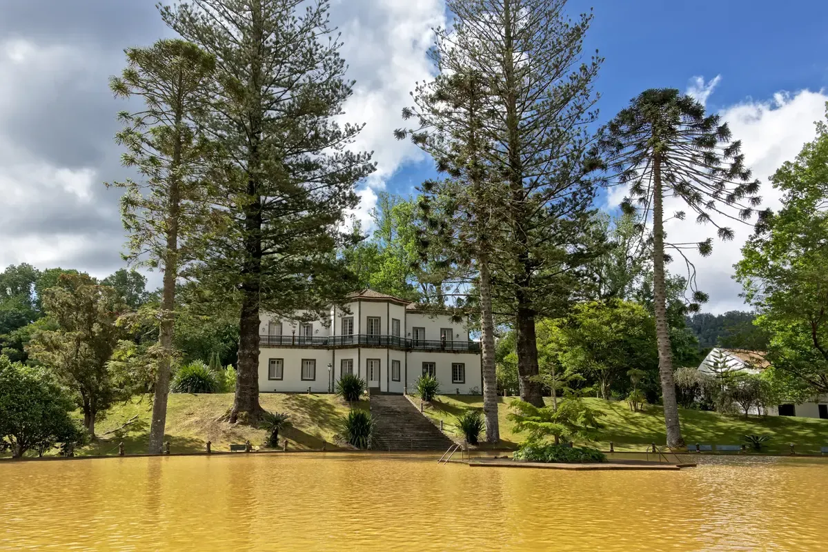 The iron thermal lake of Parque Terra Nostra with the historic building above it, Furnas