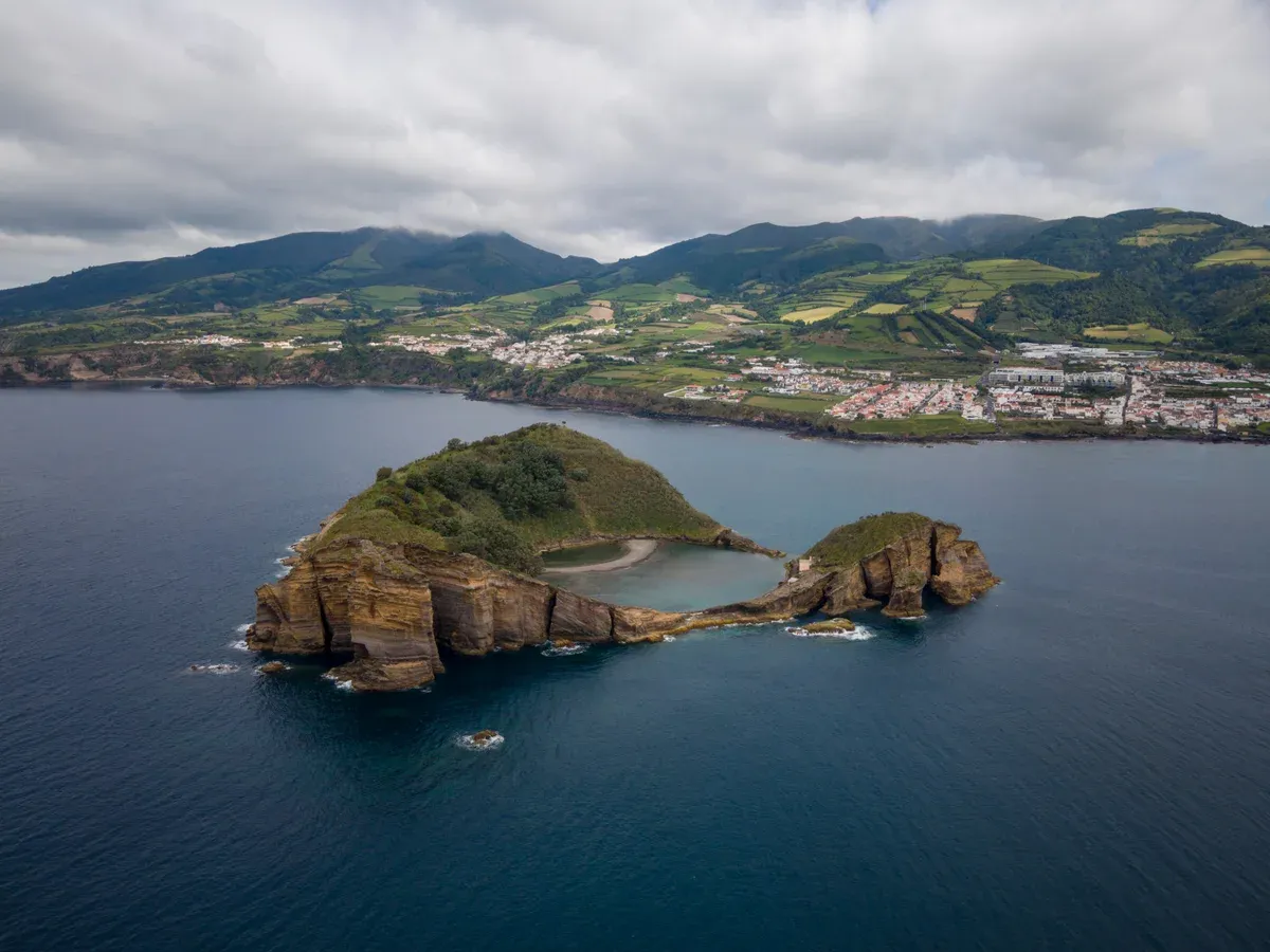 The green crater islet in the bay with the town behind it